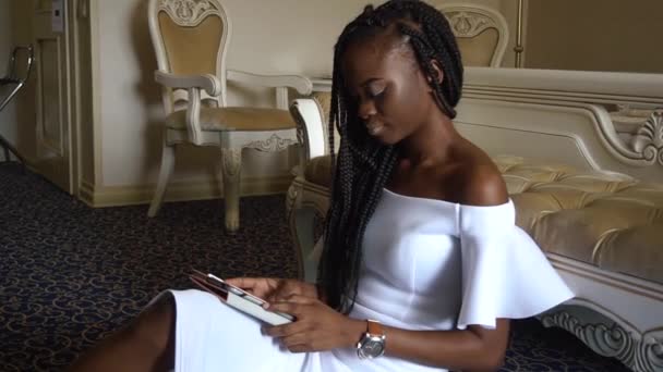 Moda şık Afro-Amerikan modeli oturma mantoyu yakınındaki ve internette sörf — Stok video