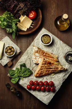 Beyaz bir plaka üzerinde beyaz ekmek maydanoz ve kırmızı kiraz domates ile sandviç