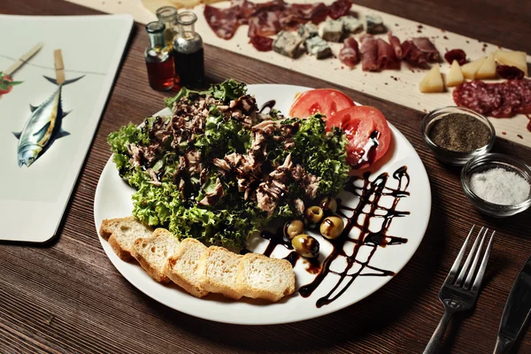 Salade van vlees, brood, olijven en olijven, basilicum. op een oude houten plank. Zwart Zebra cherry tomaten — Stockfoto