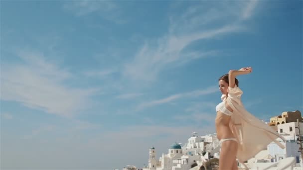 Hermosa novia morena sexy en ropa interior blanca estirándose y disfrutando de la luz del sol con el mar y las montañas en el fondo — Vídeo de stock