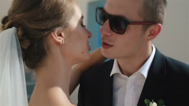 Handsome happy groom and bride in white dress kiss with stairs and corridor of hotel room on background — Stock Video