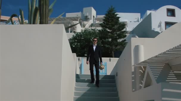 Handsome strong confident groom walks down the stairs with a bouquet in his hands — Stock Video