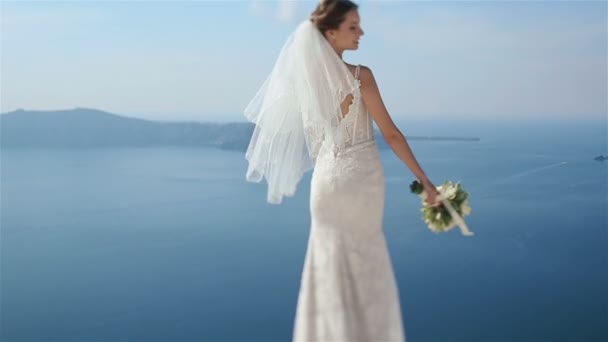 Vacker sexig brunett brud i bröllopsklänning med bukett i hennes händer ser tillbaka och leende — Stockvideo