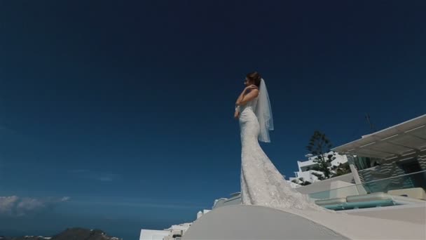 Beautiful sexy brunette bride in wedding dress with bouquet in her hands moves on the roof, Santorini closeup — Stock Video