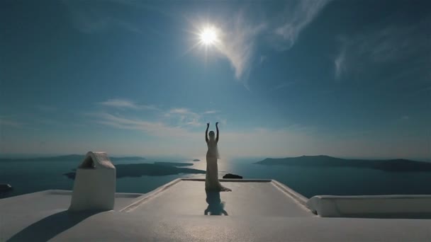 Hermosa novia morena en vestido blanco se mueve elegantemente en la terraza con fondo de mar — Vídeo de stock