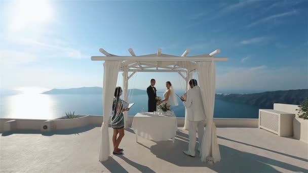 Feliz pareja casada sosteniendo ramo y mirar a los ojos de uno solo mientras se lleva a cabo la ceremonia de boda, Santorini primer plano — Vídeos de Stock