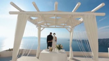 Harika esmer gelin başını Santorini Adası'nın muhteşem manzaraları izlerken onun mamülleri omzuna koyar