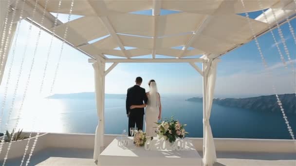 Sposo e sposa baciare a nozze corridoio tenda fondo mare, Santorino da vicino — Video Stock