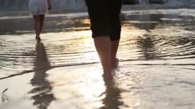 Kumsalda yalınayak günbatımı üzerinde yürüyüş ve doğa genç çifti.