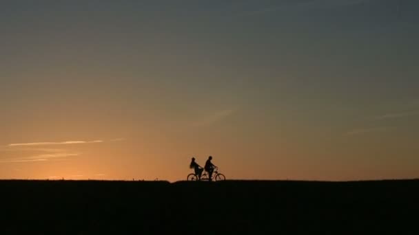 Silhouette di Bella Coppia Equitazione Tandem Biciclette Mentre Tramonto. Estate Natura sfondo con belle nuvole nel cielo Close Up — Video Stock