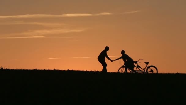 Silhouet van Beautiful Couple met Tandem fietsen spelen, de dwaas tegen zonsondergang op de achtergrond close-up — Stockvideo