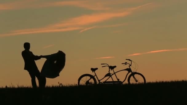Romantyczna para z Rowery-tandemy łagodnie trzymając się za ręce podczas zachodu słońca. Tło lato natura piękne chmury na niebie — Wideo stockowe