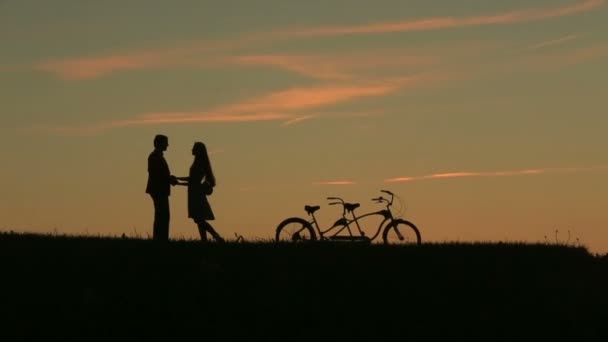 Романтическая пара с тандемом Велосипеды мягко целуются в то время как закат. Летний фон природы с красивыми облаками в небе Close Up — стоковое видео