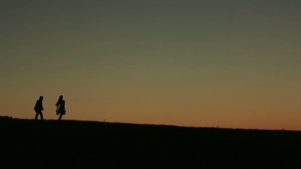 Silueta de hermosa pareja jugando captura contra puesta de sol en el backgrund primer plano — Vídeos de Stock