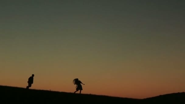 Silueta de hermosa pareja jugando captura contra puesta de sol en el backgrund primer plano — Vídeo de stock