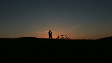 İki kişilik bisiklet günbatımı öpüşme ile romantik çift. Yaz doğa arka plan güzel bulutlar gökyüzünde ile yakın çekim