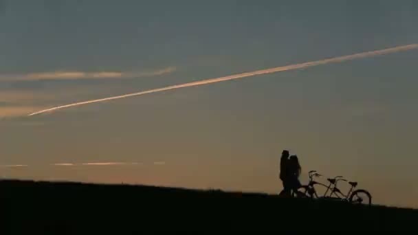 Romantikus pár a Tandem kerékpár átölelve, míg a naplemente. Nyári természet háttér gyönyörű felhők az égen közelről. — Stock videók