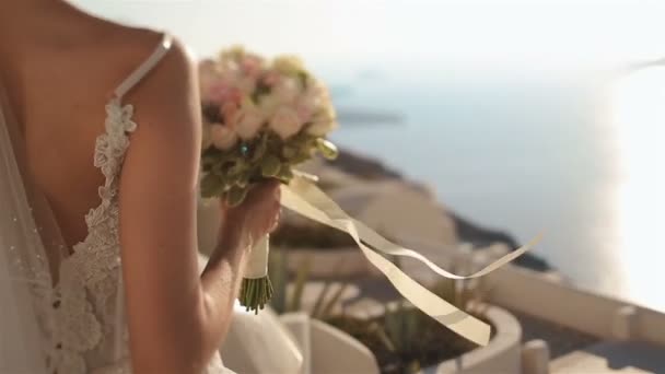 Gyönyörű barna menyasszony tart egy Rózsa csokor, miközben nézte a tenger és a hegyek — Stock videók