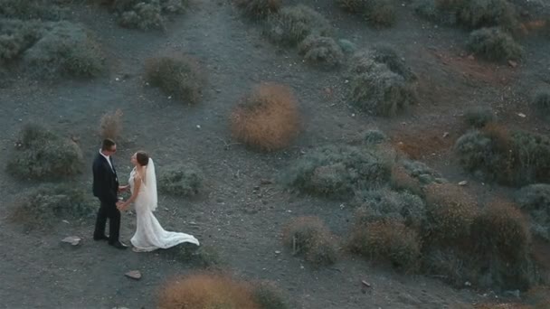 Pareja casada, novia y novio, besándose en el paisaje terrestre del volcán de montaña en Santorini, Grecia . — Vídeos de Stock