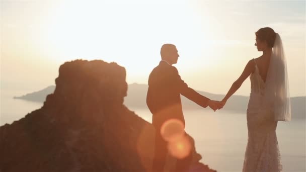 Romantiska fantastiska par ömt håller händerna tittar på utsikten på toppen av kullen på sunset himmel bakgrund — Stockvideo