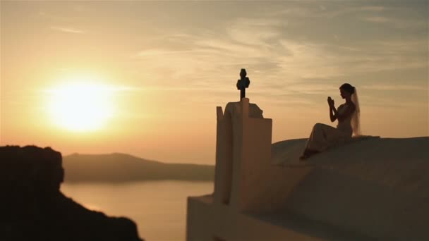 Encantadora novia reza a la cruz azul al atardecer cielo fondo — Vídeo de stock