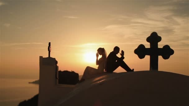 Szczęśliwe małżeństwo modli się na szczycie wzgórza, w tle niebo zachód — Wideo stockowe