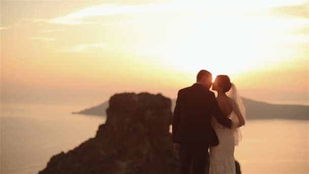 Feliz pareja casada besándose en el techo de la iglesia al atardecer cielo fondo — Vídeos de Stock