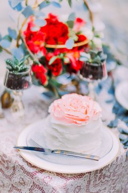 Ahşap zemin üzerine çiçeklerle süslenmiş beyaz düğün pastası