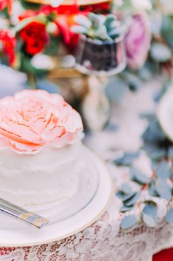 Ahşap zemin üzerine çiçeklerle süslenmiş beyaz düğün pastası