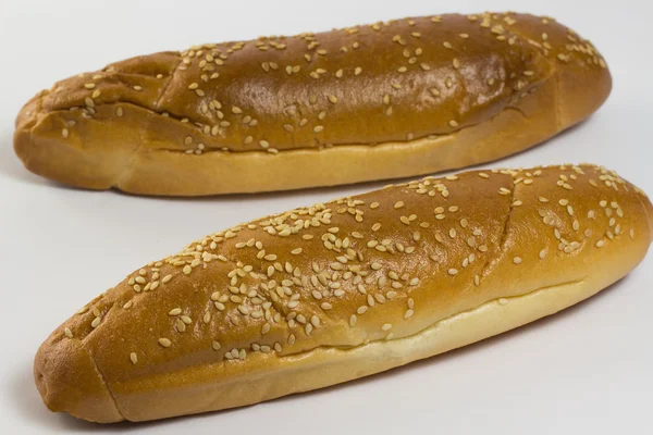 Two baguette sprinkled with sesame seeds on a white — Stock Photo, Image