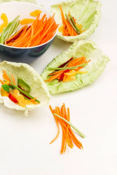 Sliced carrots. Vegan cabbage leaf snack with carrots. Bowl of carrots. White background. Flat lay. Copy space