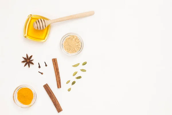 Honey and cardamom, cinnamon sticks and turmeric. Treatment of colds and flu. Traditional medicine concept. Health care. Copy space. White background. Flat lay