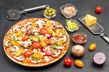 Malzemeli pizza pişirmeye hazır. Sebzeler, et, peynir rendesi, pizza bıçağı, masada nane yaprağı. Siyah arka plan. Üst görünüm