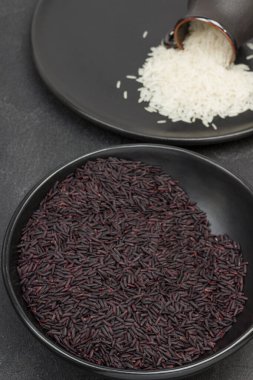 Siyah kasede siyah pirinç. Siyah tabakta beyaz basmati pilavı. Üst Manzara. Siyah arkaplan