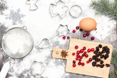 Noel pastası arka planı. Koyu kırsal yemek tepsisinde küfler, yumurta ve un. Yaban mersini ve kuru üzümler gemide. Düz yatıyordu