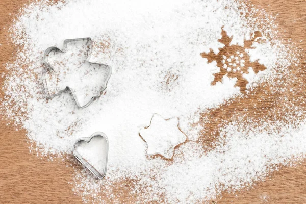 Cookie cutter molds on wooden background sprinkled with flour. Flat lay