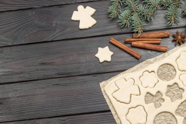 Kağıt üzerinde kalıp şeklinde kurabiyeler. Firavun dalları ve tarçın çubukları. Koyu ahşap arka plan. Uzayı kopyala Üst görünüm