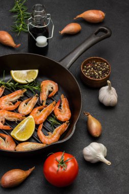 Biberiyeli karides ve tavada limon. Domates, sarımsak ve soğan. Siyah arka plan. Üst görünüm