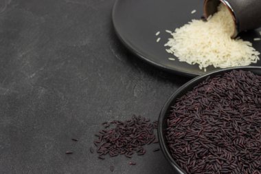 Siyah kasede siyah pirinç. Siyah tabakta beyaz pirinç. Uzayı kopyala Üst Manzara. Siyah arkaplan