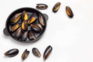 Kızartma tavasında midye. Midyeler masaya saçılmış. Uzayı kopyala Düz yatıyordu. Beyaz arkaplan