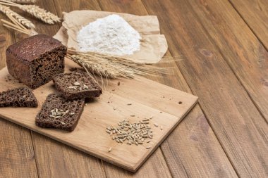 Bir dilim ekmek ve bir somun ekmek, tahtanın üzerinde çavdar ve çavdar. Kağıt üzerinde un. Uzayı kopyala Ahşap arka plan. Üst görünüm