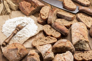 Kağıt üzerinde un ve kepçe. Masada ekmek ve bıçak dilimleri var. Kapatın. Ahşap arkaplan.