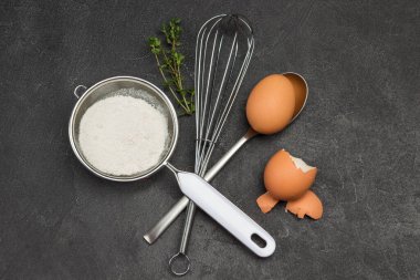 Un, çırpı, yumurta ve yumurta kabuğuyla kaşık elek. Uzayı kopyala Düz yatıyordu. Siyah arkaplan