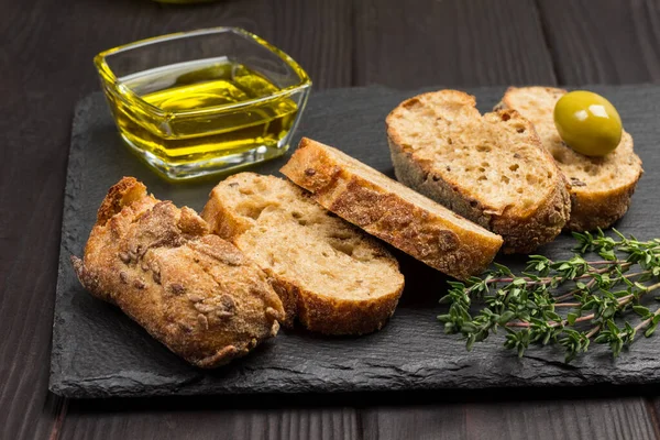 Grüne Oliven Und Brotscheiben Olivenöl Glas Und Thymianzweige Dunkler Holzhintergrund — Stockfoto