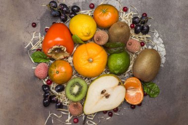 Çeşitli, çok renkli egzotik meyveler. Mandalina, greyfurt, likör, kivi ve meyve yapraklı üzüm. Paslı metal arka plan. Düz yatıyordu