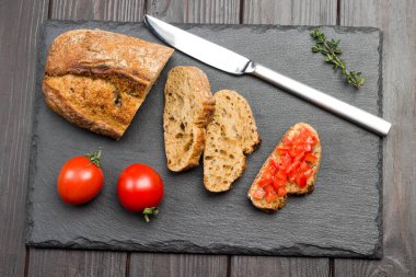 Ekmek ve bıçak parçaları. Domatesli sandviç. Lezzetli aperatif ve aperatif. Koyu ahşap arka plan. Üst görünüm
