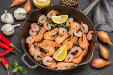 Limonlu karides ve tavada biberiye filizi. Domates, sarımsak ve soğan. Siyah arka plan. Düz yatıyordu