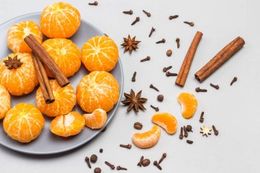 Gri kasede soyulmuş mandalina ve tarçın çubukları. Yıldız anason, tarçın çubukları ve karanfiller masada. Gri arka plan. Üst görünüm