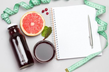 Bir dilim greyfurt, kızılcık, cam ve şişede meyve suyu, mezura. Gri arka plan. Düz yatıyordu. Boşluğu kopyala