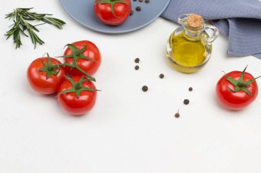 Domatesler yeşil dala. Domates ve tüm baharatlar gri tabakta. Şişede zeytinyağı. Gri peçete. Beyaz arka plan. Boşluğu kopyala